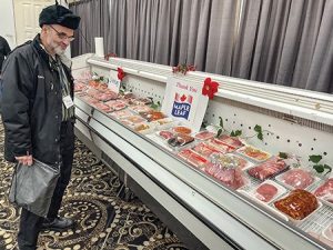 A man looks at cuts of meat in a display case.