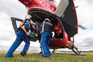 Two STARS air ambulance staff load a patient into a red helicopter.